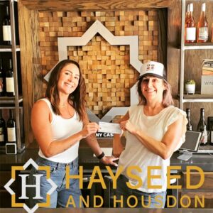 Two people toasting wine glasses in Hayseed & Housdon winery