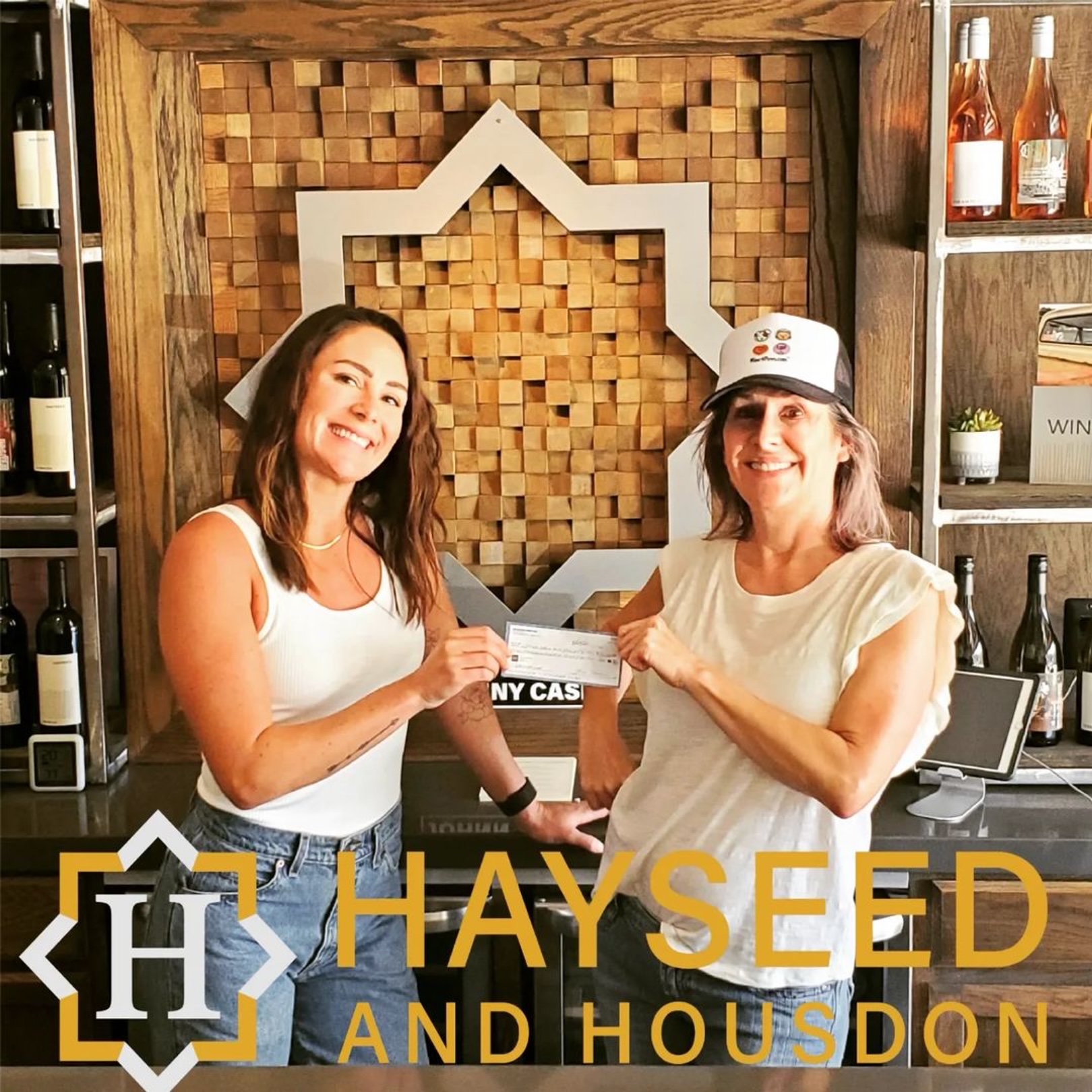 Two people toasting wine glasses in Hayseed & Housdon winery